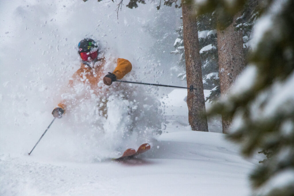 a deep powder skier in orange off-piste