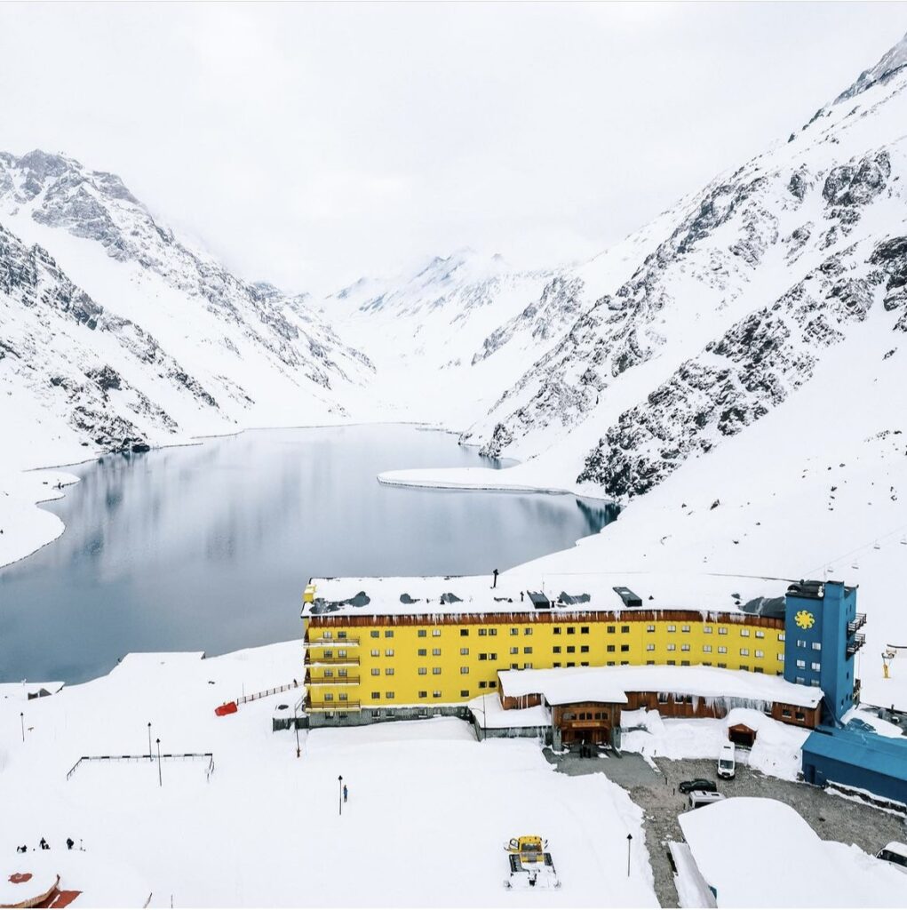 the iconic yellow Portillo base lodge covered in snow in front of the lake