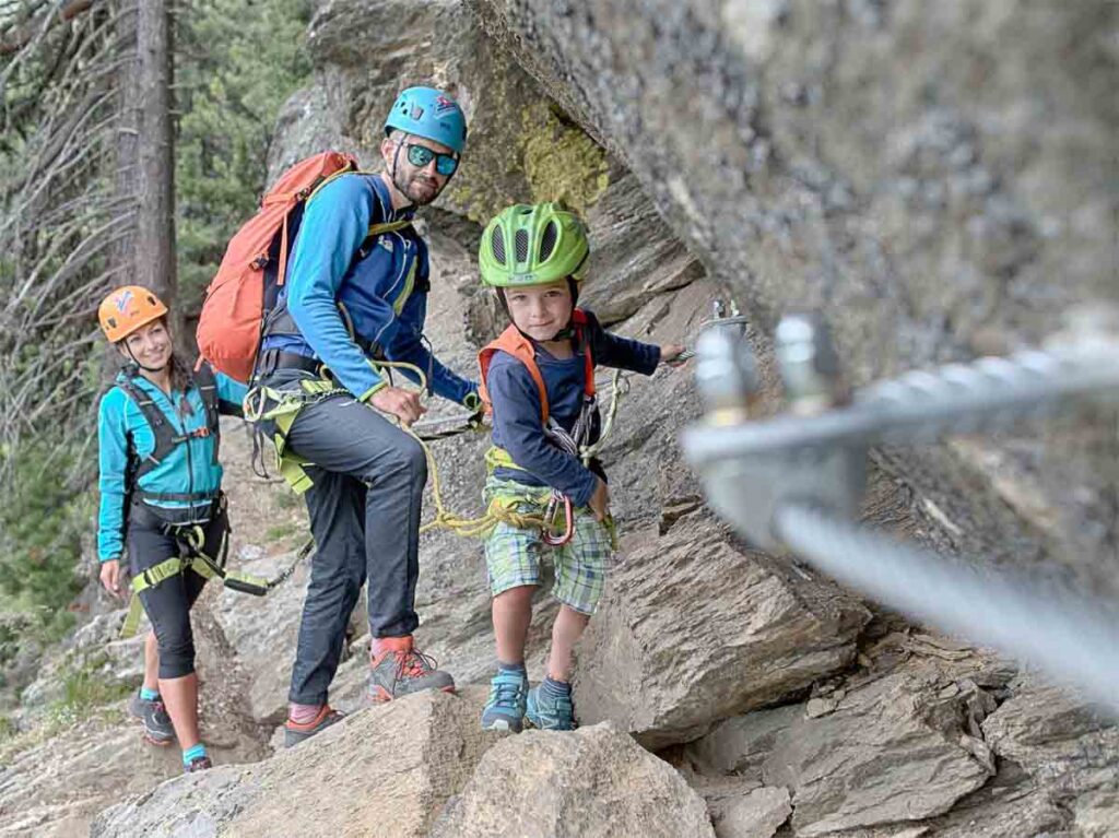 a young child and two adult on a via ferrata climbing route