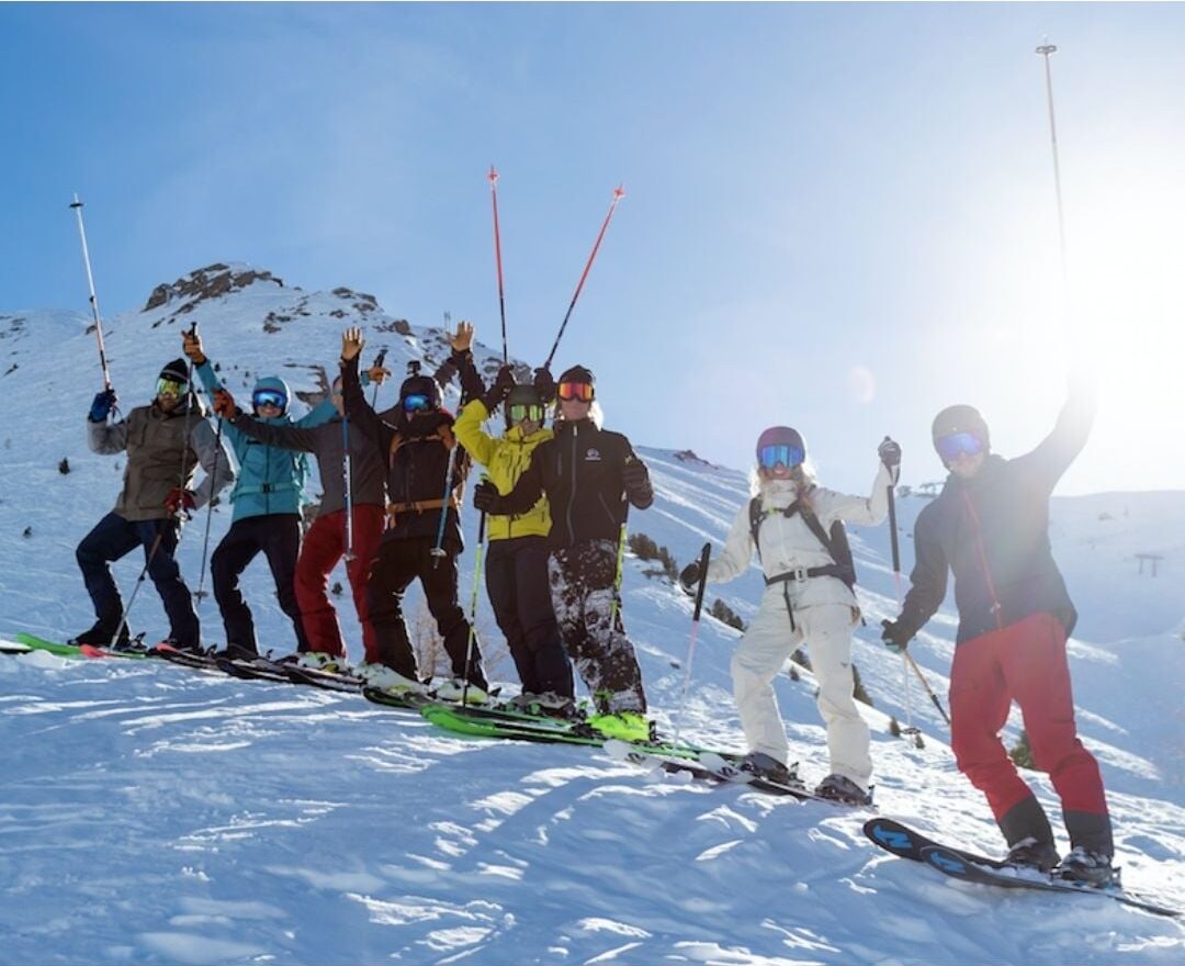 a line of skiers on the mountain, some holding poles above heads, with added text above reading 'join the crew'