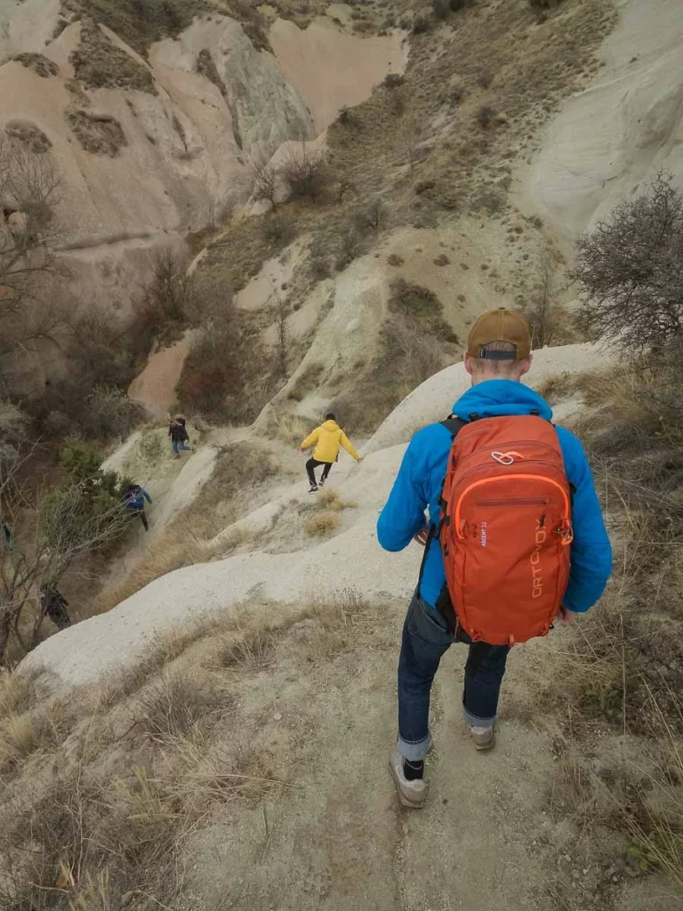 walkers head down a steep slope on smooth rocky terrain