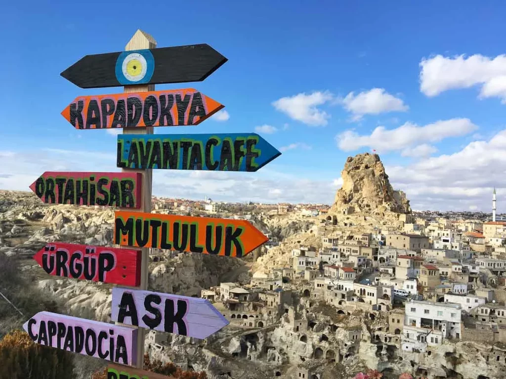 colourful hand-made signposts in front of Cappadocia town built into the rock