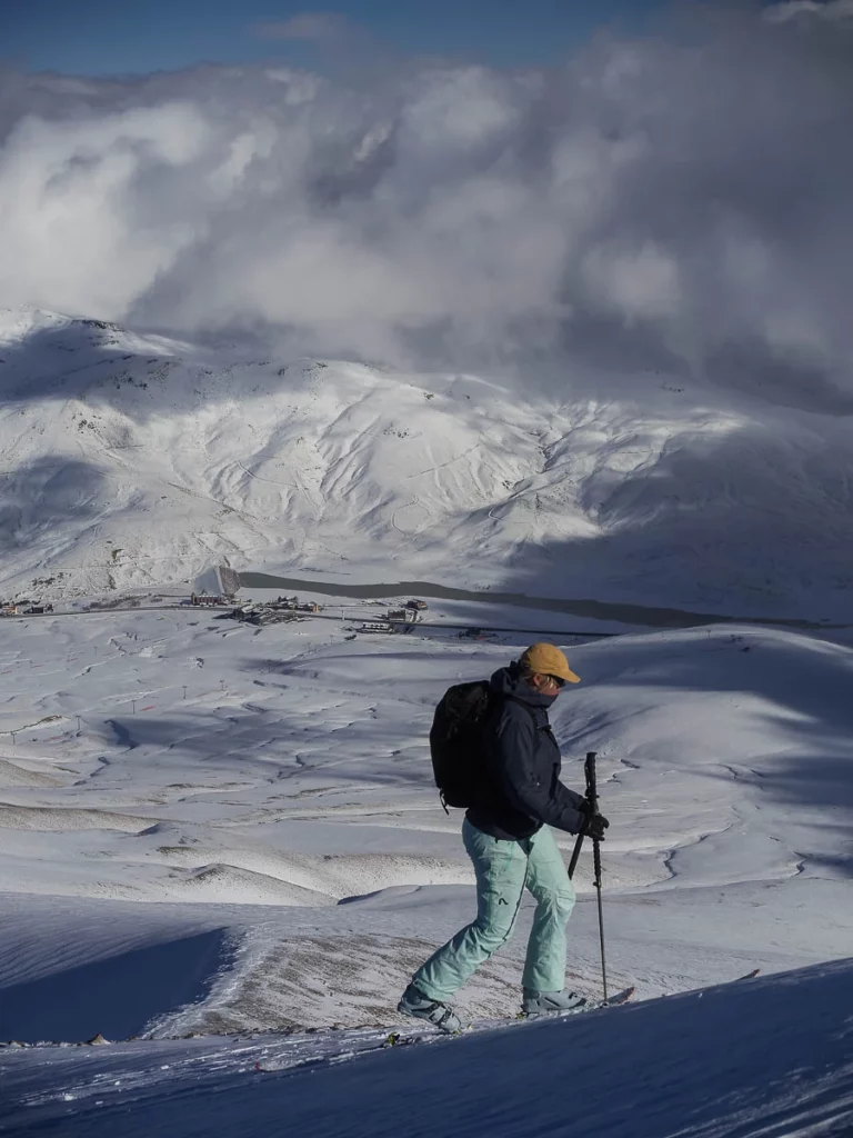 ski tourer heads uphill, the snowy valley below