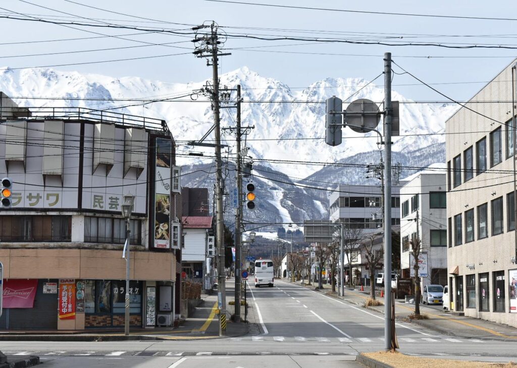 huge snowy mountains rising up from the end of a tarmac road in Japan