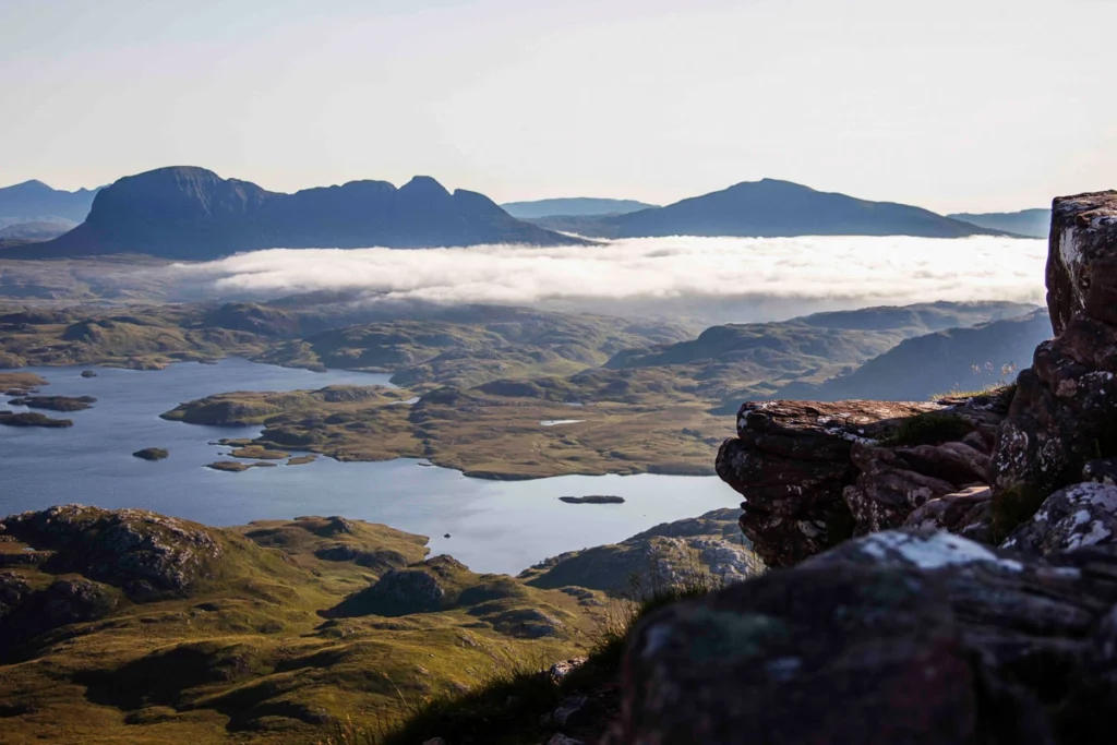 mountaintop shot of stunning Scottish scenery, loch and green hilly land far below