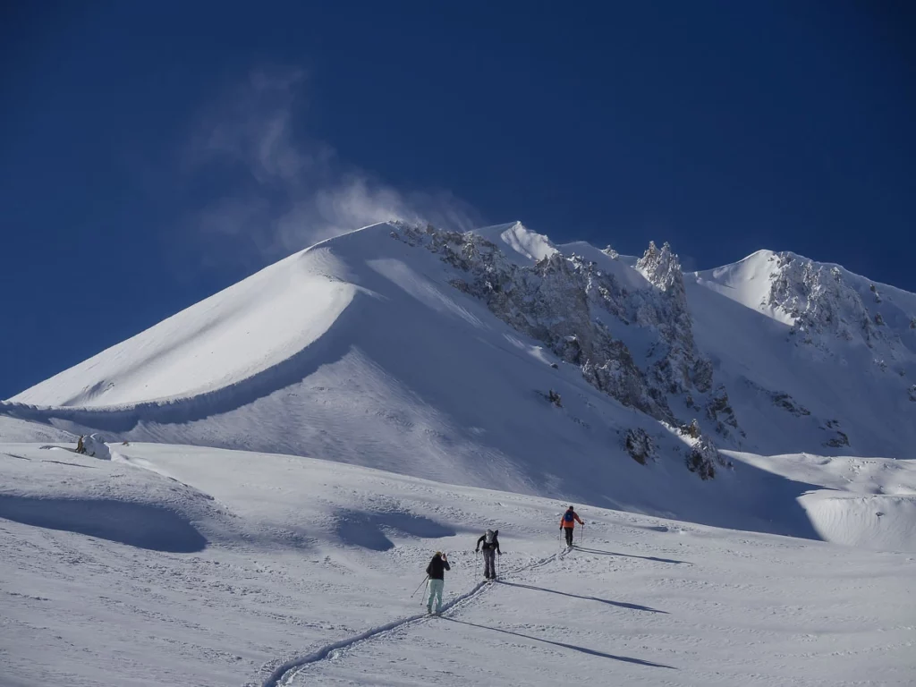 a trio of ski tourers head uphill on mellow slope