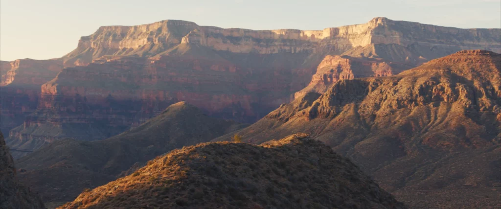 A section of the Grand Canyon is photographed, perhaps in the morning with some facets catching the light