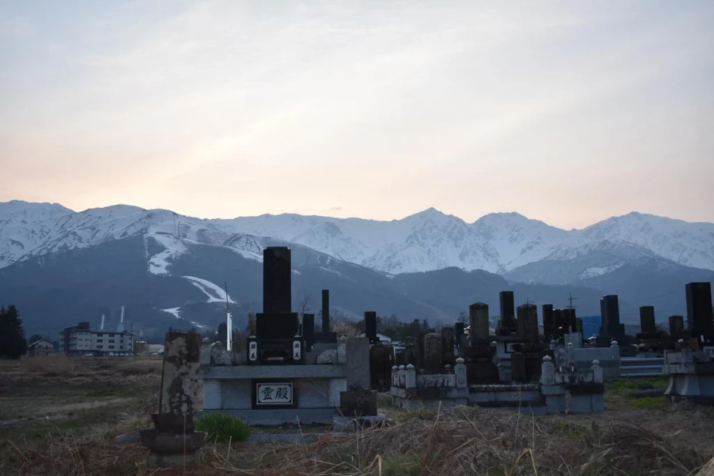 a Japanese graveyard, backed by snowy mountains and less snowy foothills