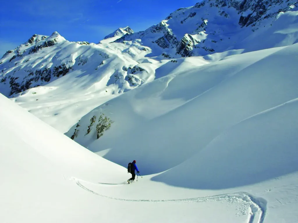 a telemark skier in a natural halfpipe makes fresh tracks in fresh snow