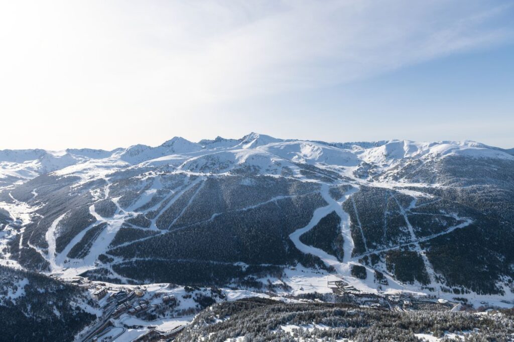 Aerial View of Grandvalira Ski Resort: Wide view of Grandvalira's extensive ski slopes and mountain ranges under a clear blue sky.