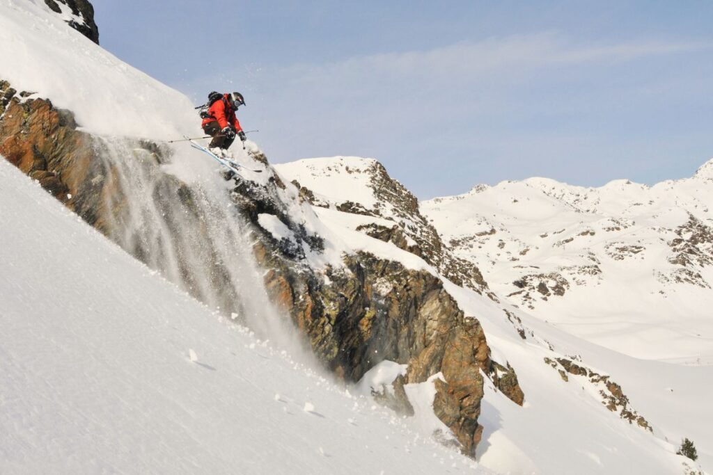 Freeride Paradise in Ordino Arcalís: A skier navigating a steep, powdery cliff face in the freeride zones of Ordino Arcalís.