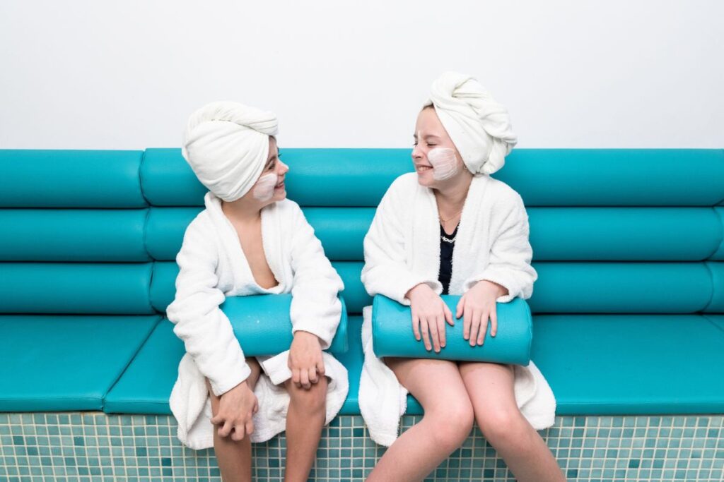 Children Relaxing at Andorra Spa: Two children wearing robes and smiling, enjoying a spa day in a bright, modern relaxation area in Andorra.